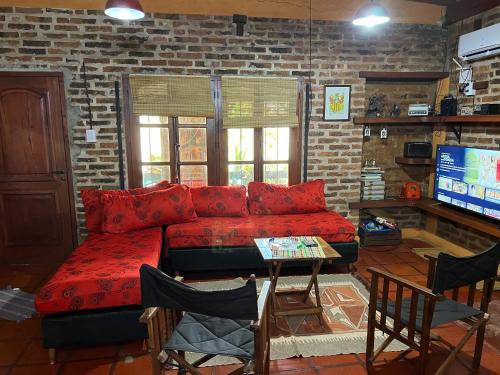 a living room with a red couch and a tv at Casa con piscina y parque in Garupá