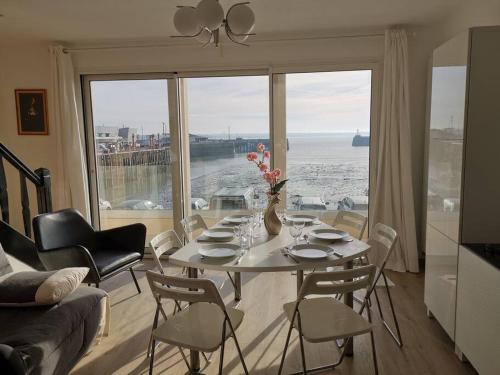 a living room with a table with chairs and a large window at Charme et zénitude, avec vue exceptionnelle sur le port in Granville