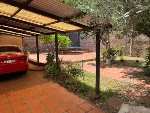 a red car parked under a pavilion in a driveway at Casa con piscina y parque in Garupá