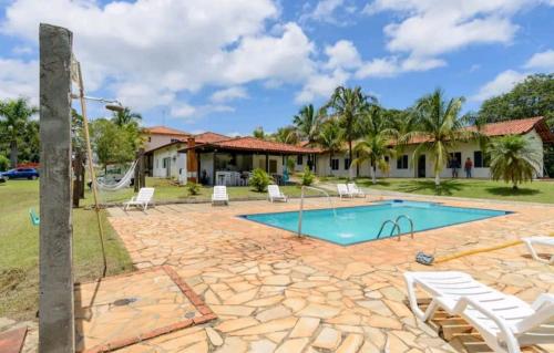 a swimming pool with chairs and a house at Pousada Ferradura in São Pedro