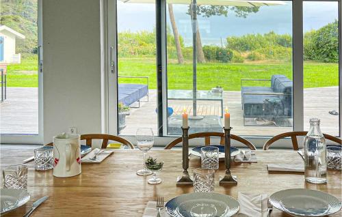 einen Esstisch mit Stühlen und ein großes Fenster in der Unterkunft Beautiful Home In Skivarp With House Sea View in Skivarp