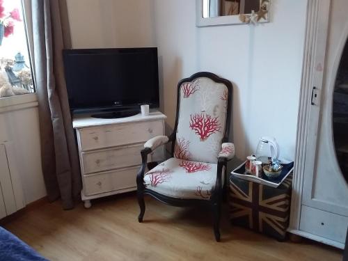 einen Stuhl in einem Zimmer mit einem TV und einem TV. in der Unterkunft LES BIGORNEAUX in Saint-Suliac