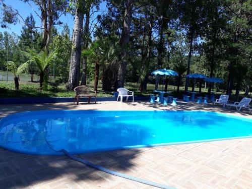 a blue swimming pool with chairs and tables and umbrellas at Harry World Parque Hotel in Curitibanos