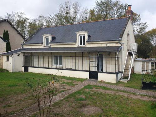 uma grande casa branca com um telhado preto em Maison de village au bord de l'Indre au calme em Avoine