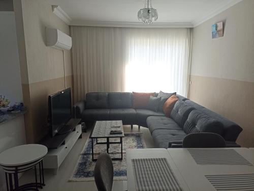 ein Wohnzimmer mit einem Sofa und einem TV in der Unterkunft ManavgatApartment in Manavgat