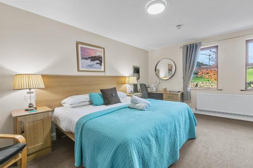 Tollyrose Country House في نيوكاسل: غرفة نوم بسرير كبير مع بطانية زرقاء