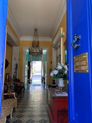 a hallway with a blue door and a chandelier at Hôtel Château des Jacobins in Agen
