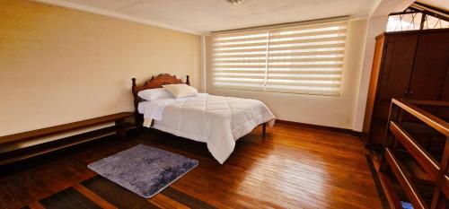 1 dormitorio con 1 cama y ventana con persianas en TU CASA EN MACAS en Macas