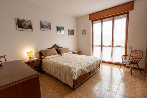 1 dormitorio con cama, mesa y ventana en Appartamento vista Alpi biellesi, en Biella