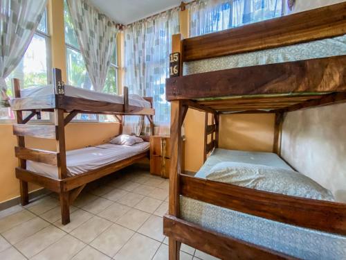 two bunk beds in a room with a window at The Driftwood Surfer Beachfront Hostel / Restaurant / Bar, El Paredon in El Paredón Buena Vista