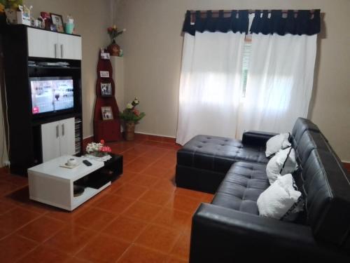 a living room with a black leather couch and a tv at La Casa de Estela in La Paz