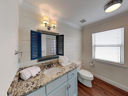 een badkamer met een wastafel, een toilet en een spiegel bij Muskoka C in Gulf Shores