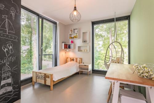 a bedroom with a bed and a desk and windows at Villa Merici in Bergen