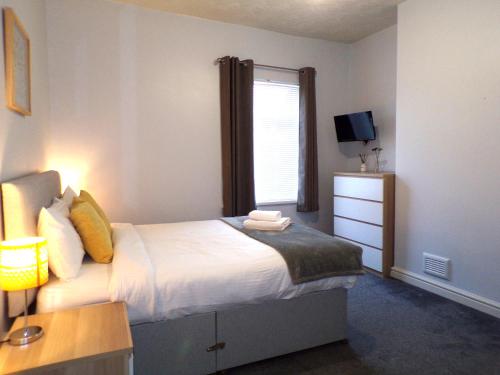 a small bedroom with a bed and a window at Lynam House in Stoke on Trent