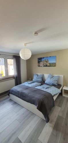 a white bedroom with a large bed with blue pillows at Ferienwohnung Teufelsmauer in Timmenrode