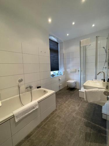ein Badezimmer mit einer Badewanne, einem Waschbecken und einem WC in der Unterkunft Hotel Lingemann in Wallenhorst