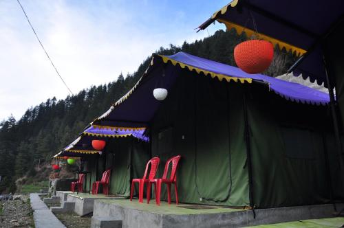 eine Gruppe roter Stühle in einem grünen Zelt in der Unterkunft Barot , Waterfall Camps and Domes I Best seller in Mandi