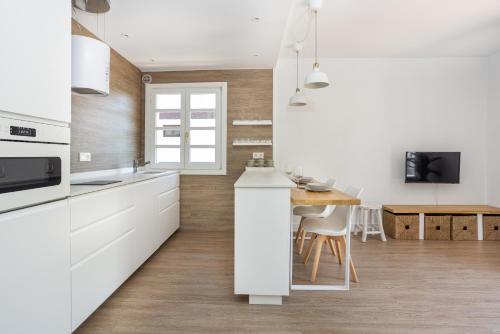 cocina con armarios blancos y mesa de madera en Apartamento turístico Legate, en Elizondo