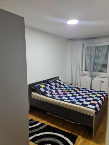 a bedroom with a bed with a checkered blanket at Apartman Jaca in Tuzla