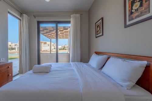 1 dormitorio con 1 cama blanca grande y ventana en Brand-New Family House in Tawila El Gouna Lagoon and Pool Access en Hurghada