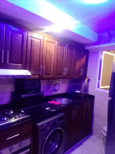 una cocina con armarios de madera, lavadora y fregadero en عقارات مرتيل, en Martil