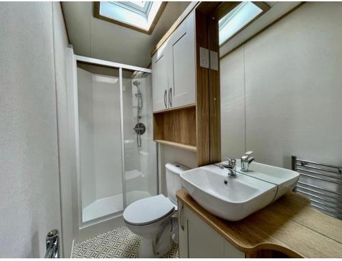 a bathroom with a sink and a shower and a toilet at Prime Location Selsey Chalet Seal Bay in Selsey
