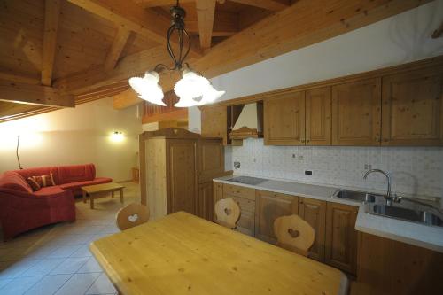 a kitchen with wooden cabinets and a table and a couch at Appartamenti Villa Elisa in Falcade