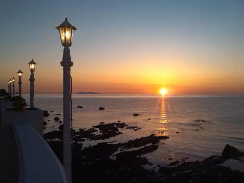 una puesta de sol sobre el océano con una luz de la calle en Hotel Ariana, en Marine du Miomo