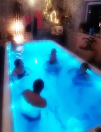 un groupe de personnes dans une piscine la nuit dans l'établissement Fairytale Memories, gîte, spas et féerie, à Varsberg
