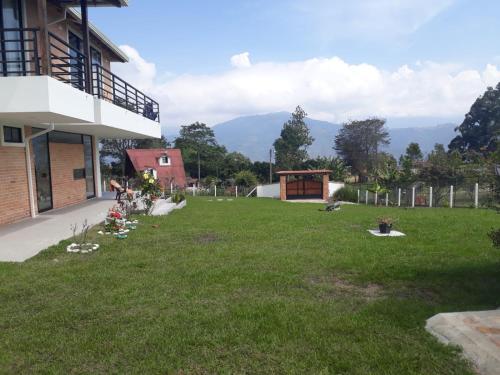 a green yard with a building and mountains in the background at Casa Campestre Altamira in Los Curos