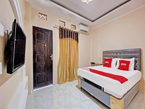 um quarto com uma cama com almofadas vermelhas e uma porta em OYO 92193 Kos 21 em Kupang
