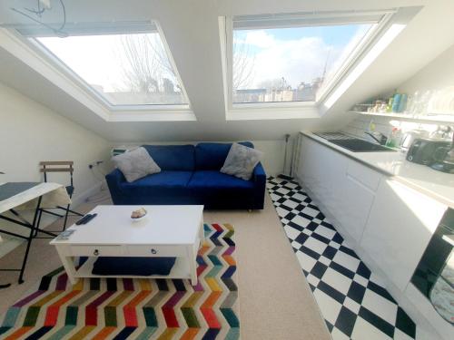 sala de estar con sofá azul y 2 ventanas en Jacuzzi Suite, en Londres