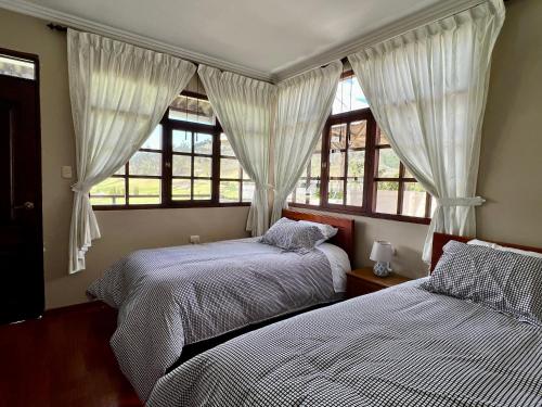 two beds in a bedroom with windows at Estancia Jardín de Teresita 