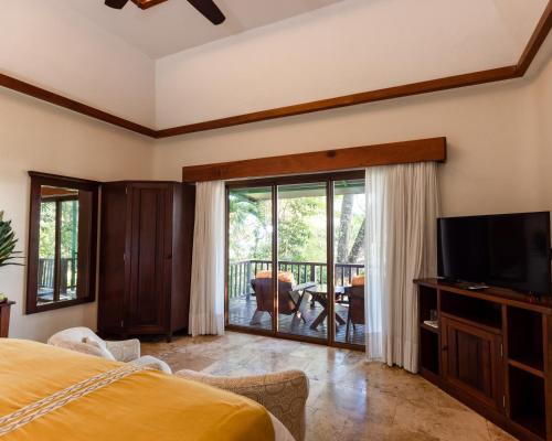 a bedroom with a bed and a tv and a balcony at Bolontiku Boutique Hotel & Spa in Flores