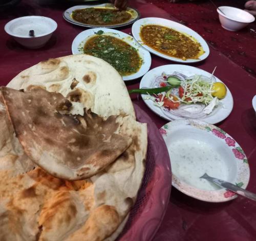 een tafel met borden en schalen van voedsel bij Karachi Guest House & Couple Hotel in Karachi