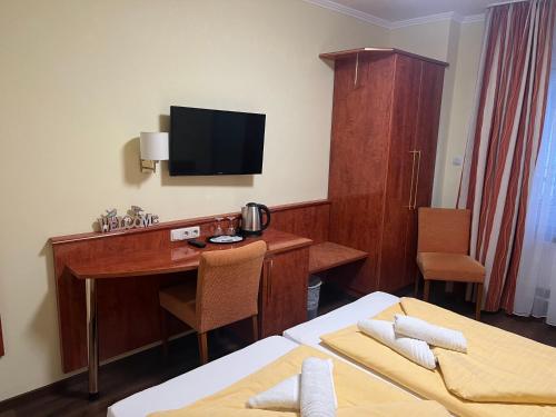 a hotel room with a desk and a television at M&M Hotel - Seevetal in Seevetal