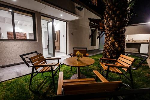 a patio with a table and chairs and a palm tree at Chacras Wineland Lodge - Casa West in Ciudad Lujan de Cuyo