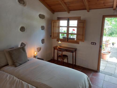 Casa Rural Chamorga في سانتا كروث دي تينيريفه: غرفة نوم بسرير ومكتب ونافذة