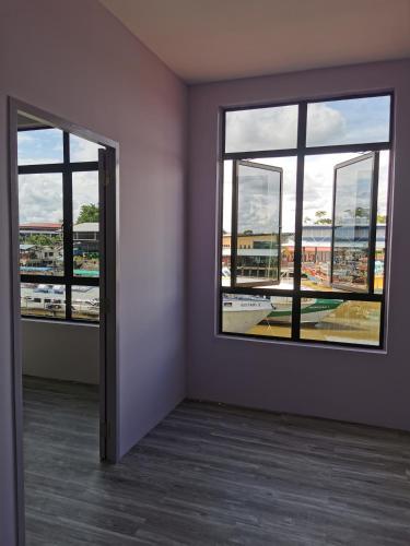 an empty room with two windows and a view of a city at MersingFirstFloor丰盛港二楼民宿 in Mersing