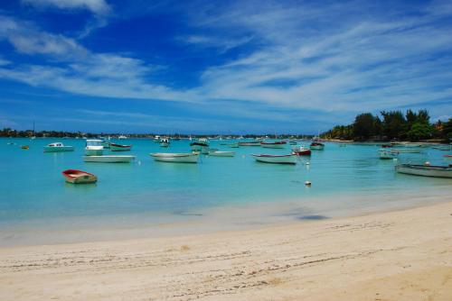 a bunch of boats in the water on a beach at Résidence Bleu Azur in Grand Baie
