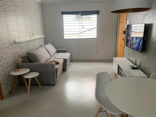 a living room with a couch and a table at Apto 1o andar novo 2 Dorm - próximo ao centro in Poços de Caldas