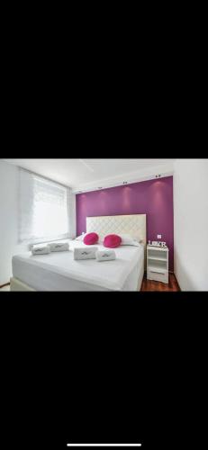 - une chambre avec un grand lit et un mur pourpre dans l'établissement Villa White Pearl in Slivno, à Slivno