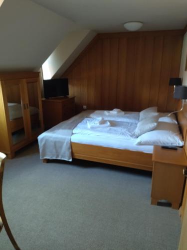 - une chambre dotée d'un grand lit avec des draps et des oreillers blancs dans l'établissement Penzion Joštovka, à Jihlava