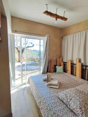 une chambre avec un lit et une grande fenêtre dans l'établissement Arche de Noé atypique, bohème , nature, piscine chauffée de Pâques à Toussaint , spa , sauna , loisirs, au Beausset