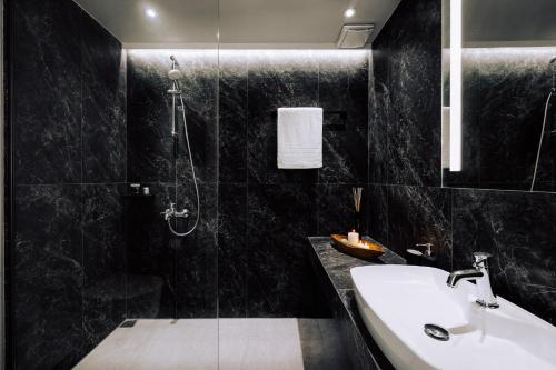 a black bathroom with a sink and a shower at Suite Homes - Fine Living , Preveza in Kanali