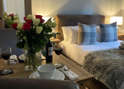 a table with a vase of flowers and glasses of wine at Stonehenge Cottages in Salisbury