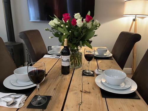a wooden table with a bottle of wine and flowers at Stonehenge Cottages in Salisbury