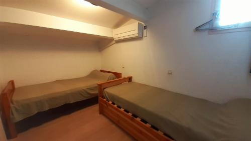 deux lits dans une petite pièce avec une fenêtre dans l'établissement MAISONS DU GOLF Joli villa mitoyenne proche plage Richelieu Cap d'Agde, au Cap d'Agde