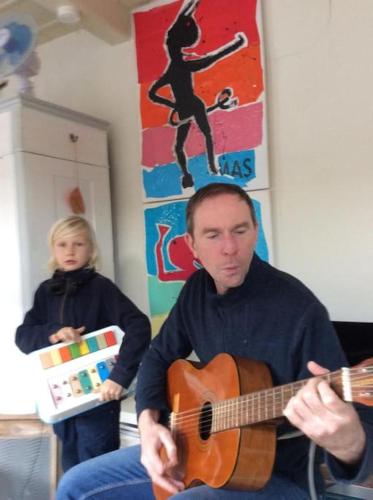 a man playing a guitar next to a child at westcoast-Speicher in Friedrichstadt
