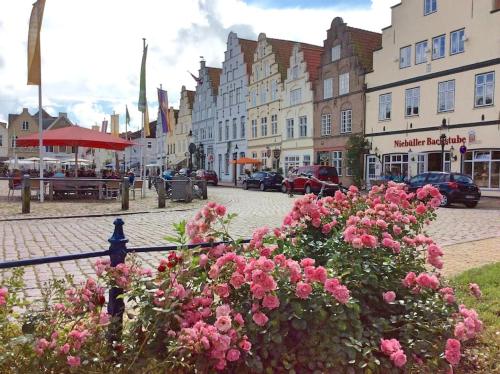 een straat met roze bloemen voor gebouwen bij westcoast-Speicher in Friedrichstadt